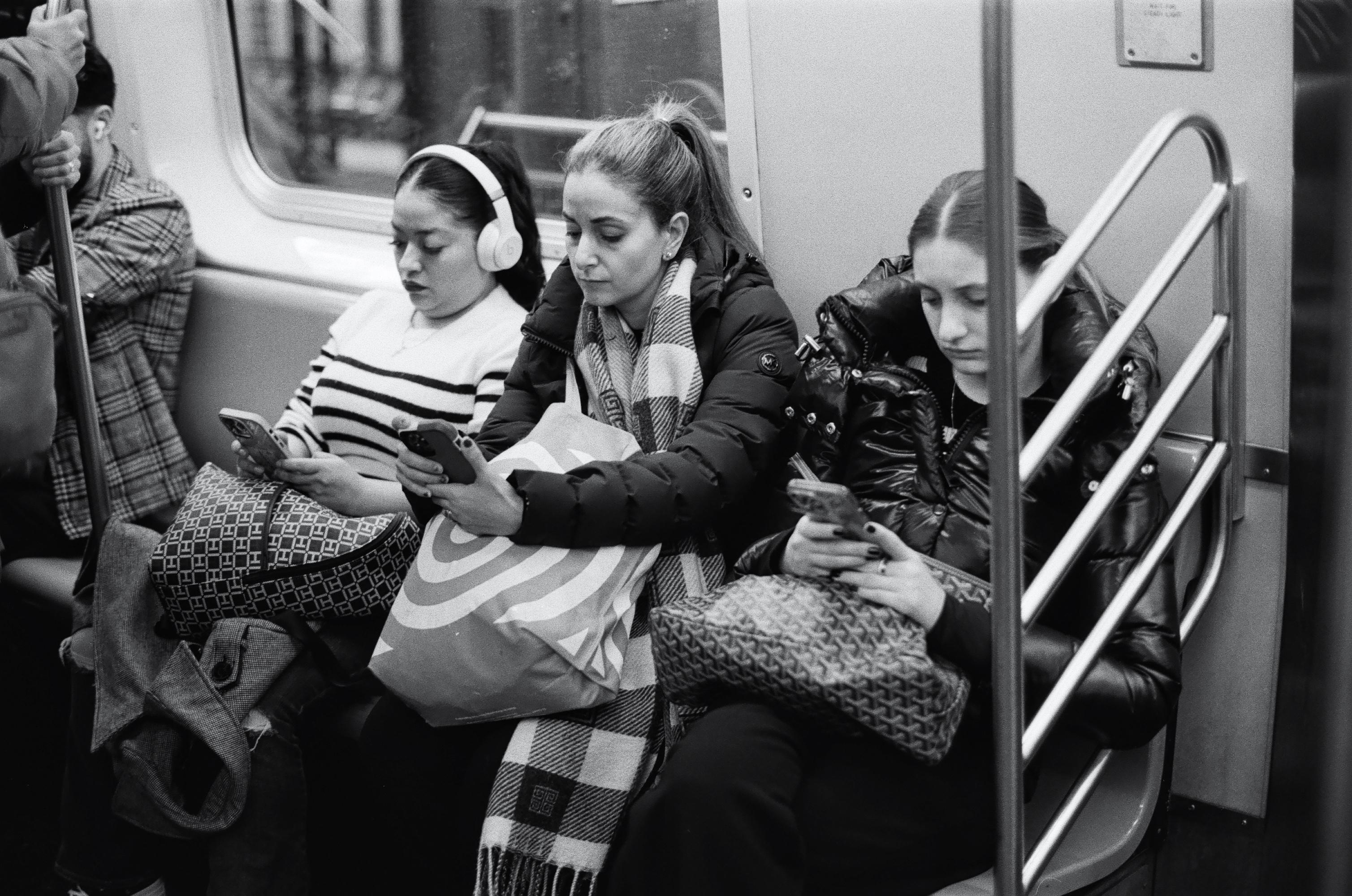 Passengers using their smartphones aboard a New York City subway train, December 9, 2022