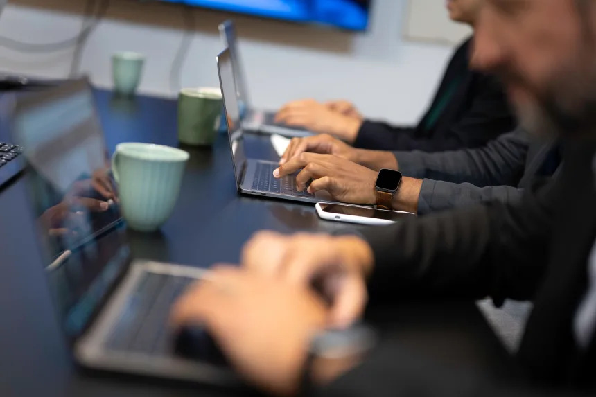 People work on laptops in an office as AI changes the kinds of tasks many white-collar jobs involve.